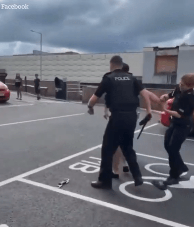 Police officers arresting a person in a parking lot.