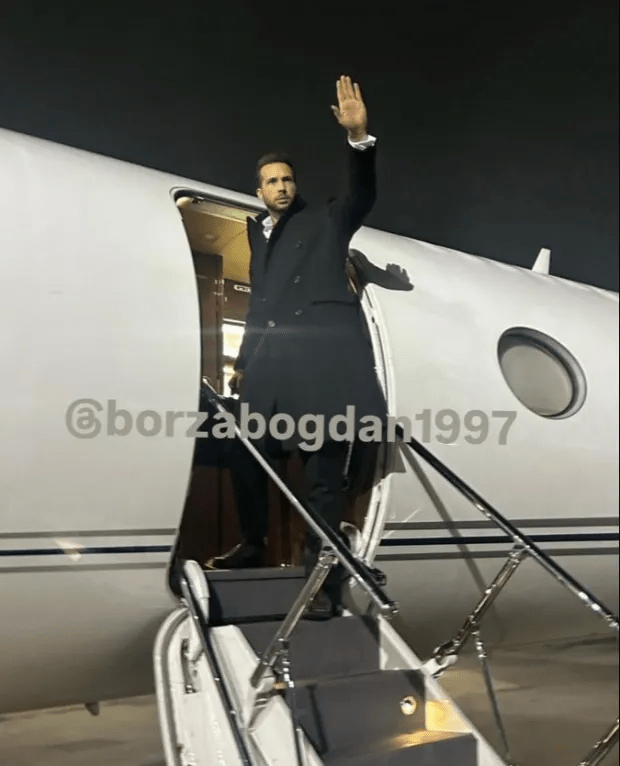 Man in suit exiting private jet, waving.
