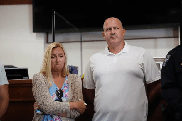 A man and woman standing with arms crossed.