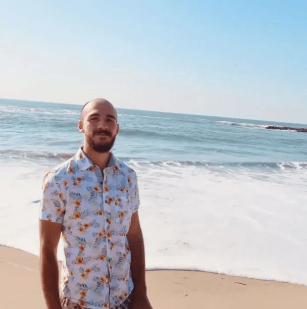 Man in floral shirt on beach.