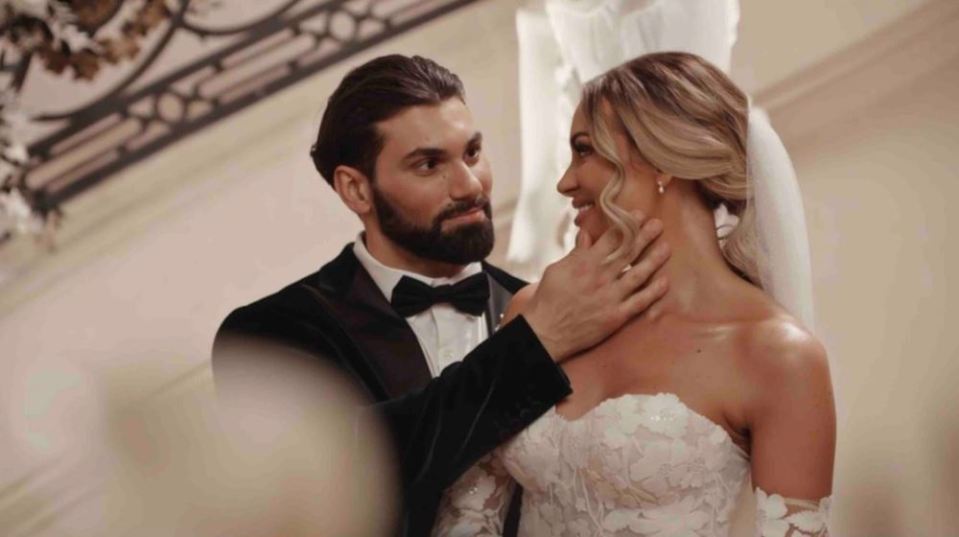 A groom gently touches his bride's face.