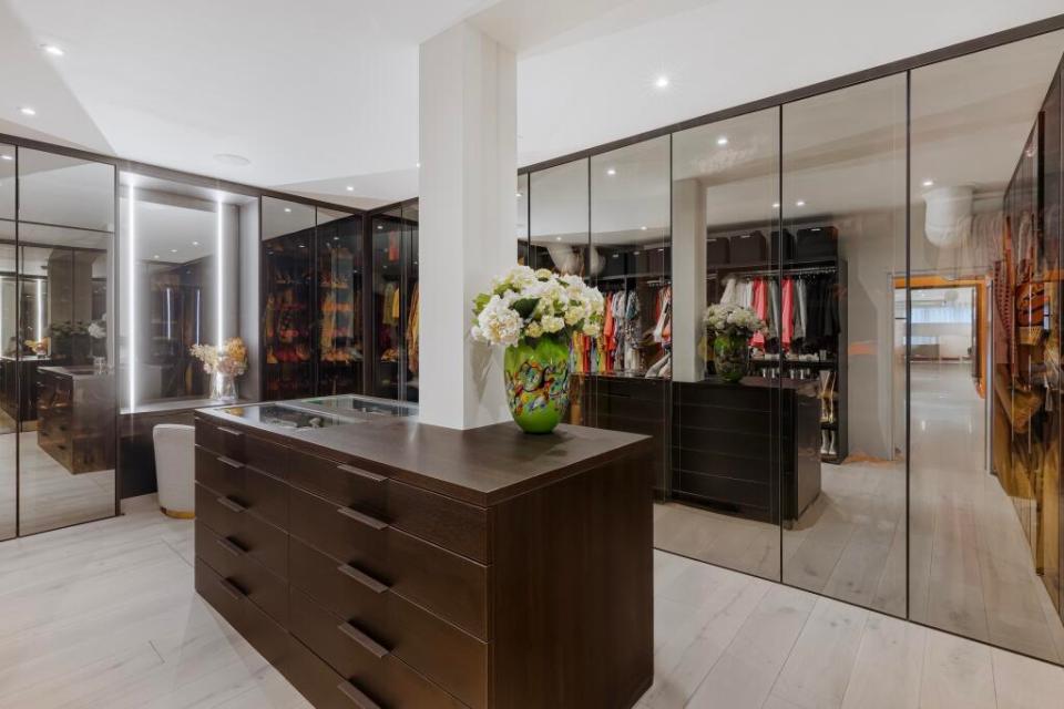 Interior view of a large walk-in closet with dark wood cabinetry and mirrored walls.