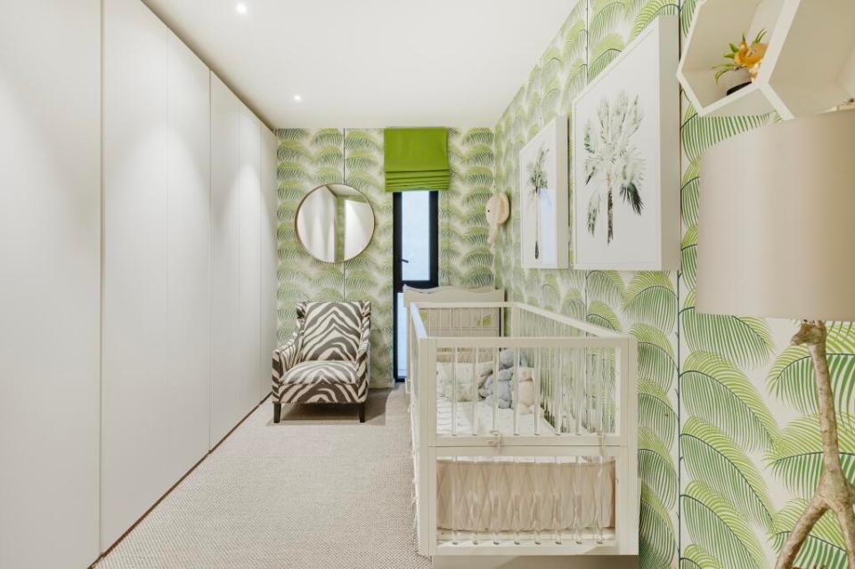 Nursery with crib and palm tree wallpaper.