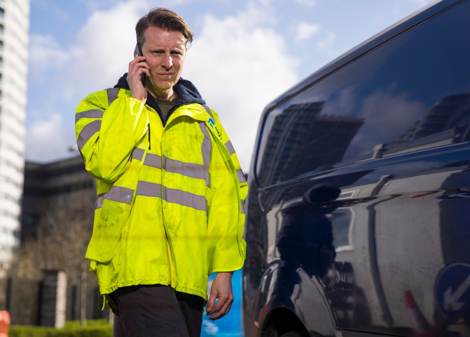 Man in a high-visibility jacket using a mobile phone.