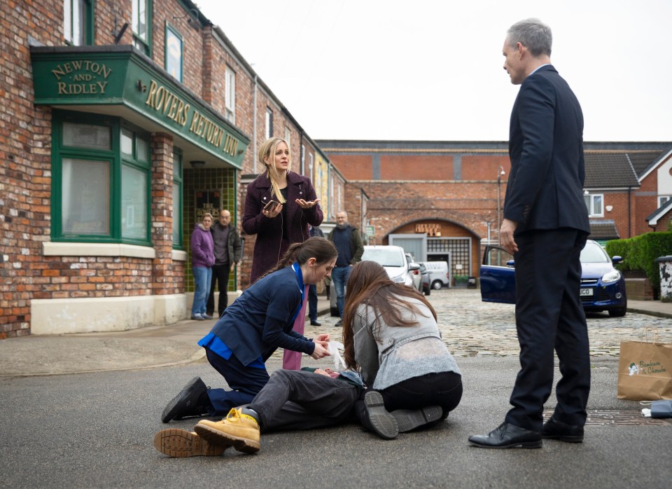 Scene from Coronation Street showing several characters attending to two injured people lying on the ground.
