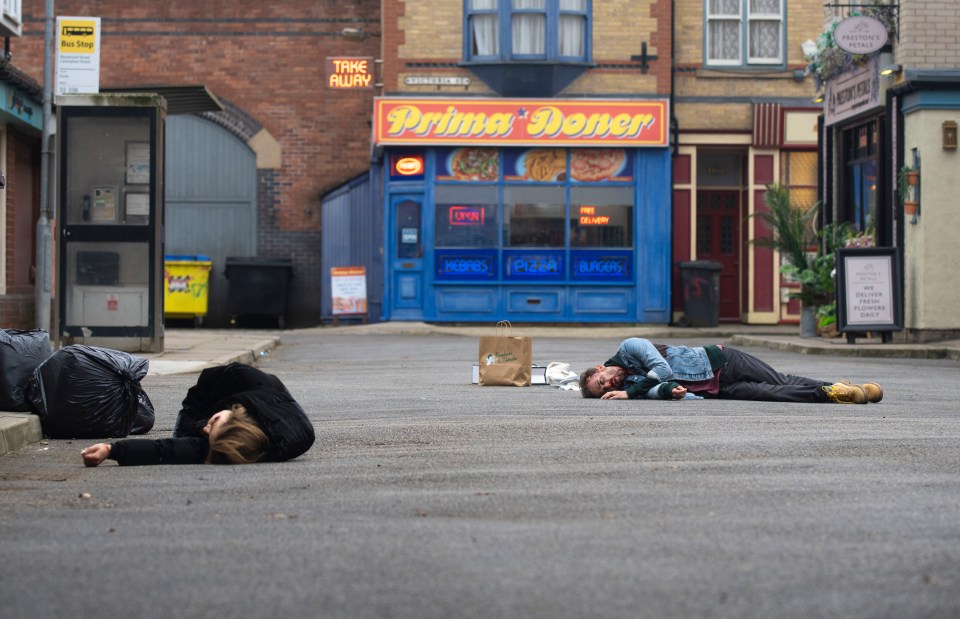 Two people lying injured on the street.