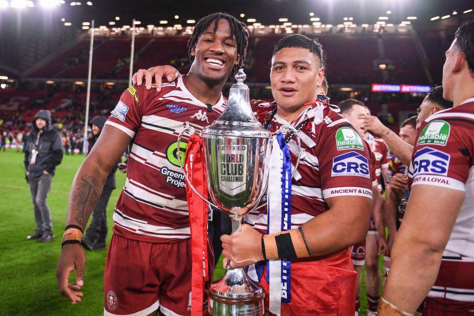 Junior Nsemba and Patrick Mago of the Wigan Warriors holding a trophy.