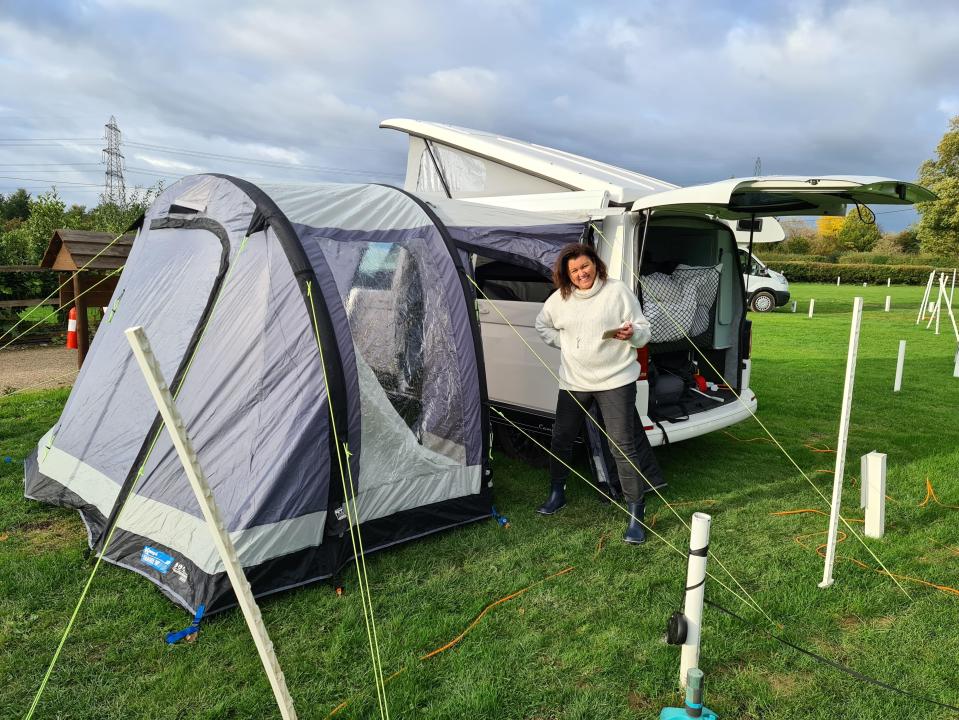 Woman standing near a pop-up tent and campervan.