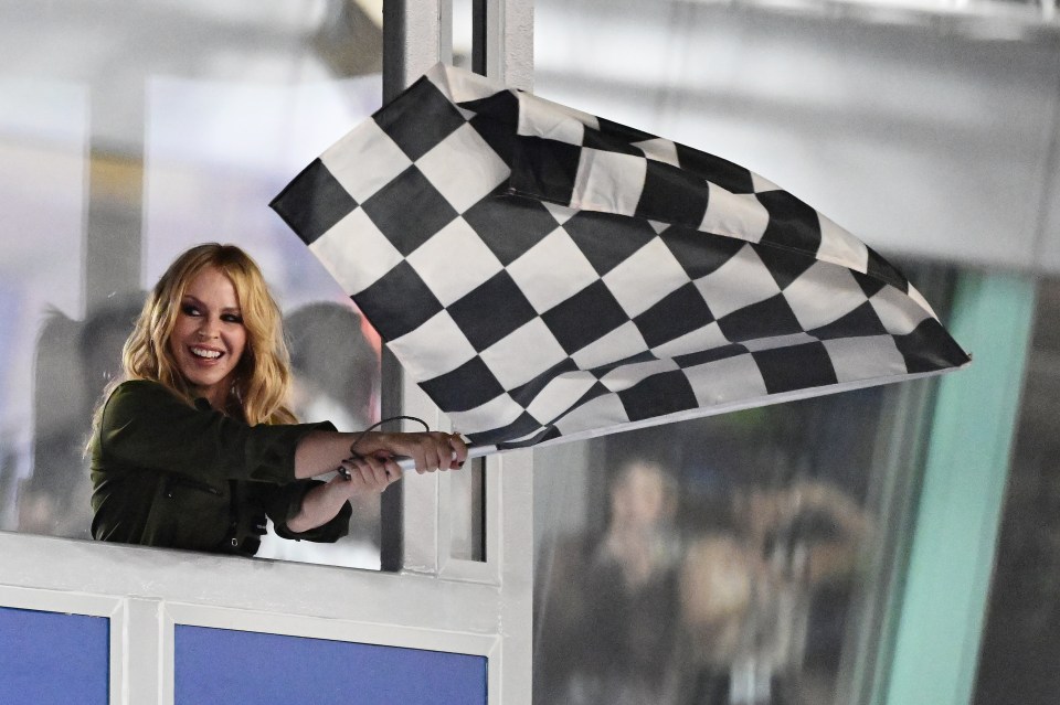 Kylie Minogue waves a checkered flag.