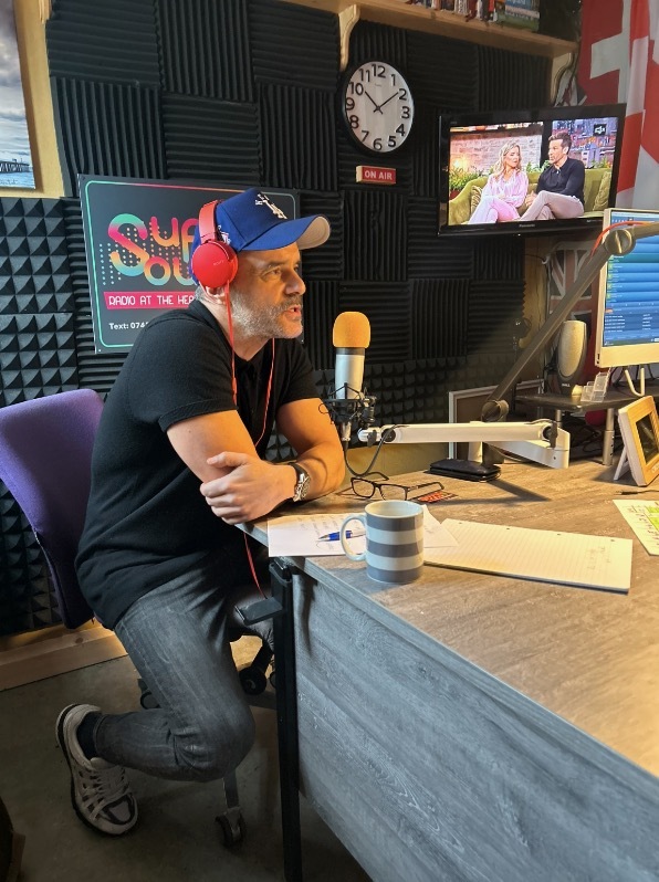 Man in a radio studio speaking into a microphone.