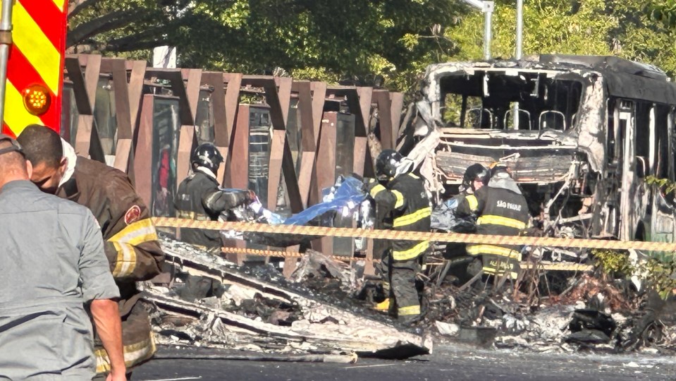 Aftermath of a plane crash in Sao Paulo, showing a burned-out bus and plane wreckage with firefighters at the scene.