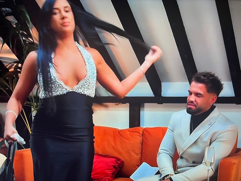 A woman in a sparkly dress storms off while a man in a suit sits calmly.