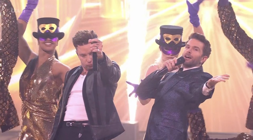 Two singers performing on stage with backup dancers.