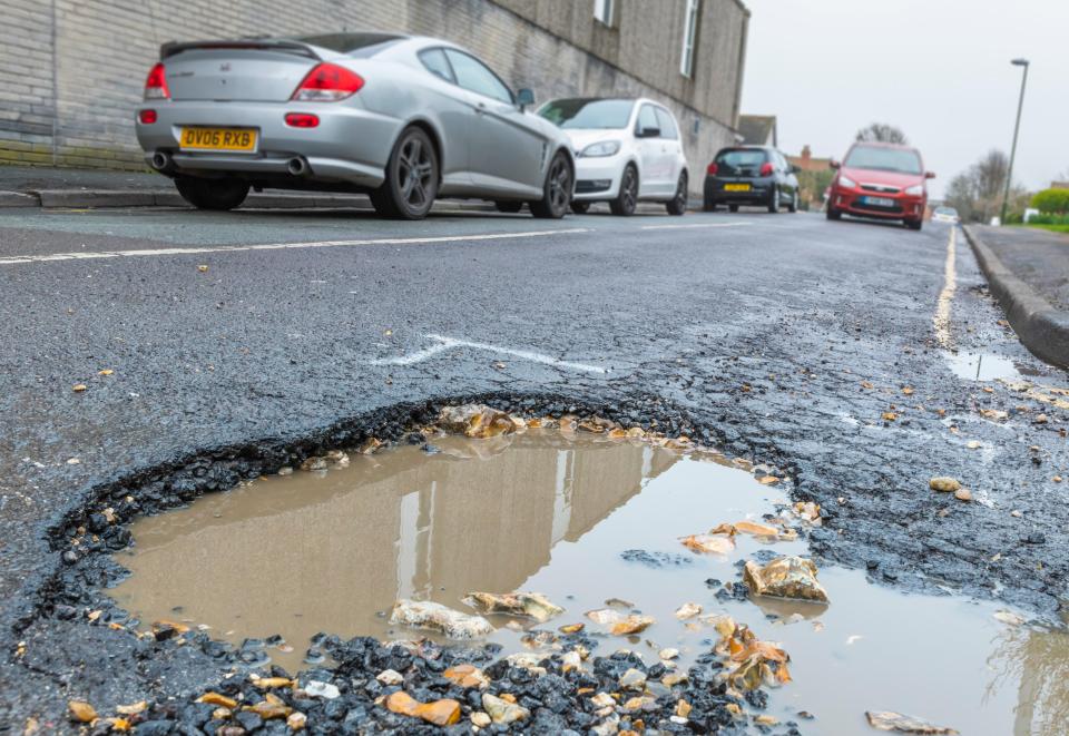 Large pothole filled with rainwater in a road.