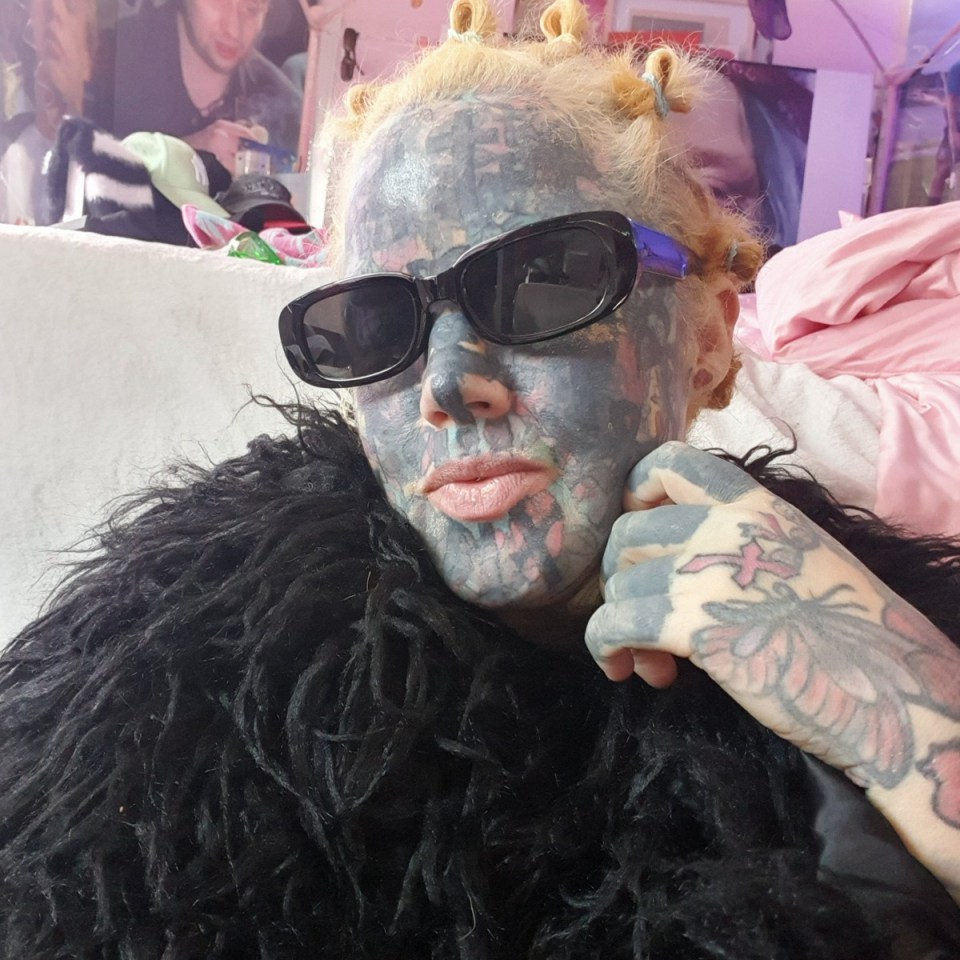 Portrait of a heavily tattooed woman wearing sunglasses.