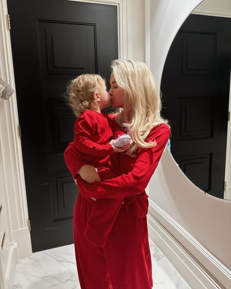 Woman in red pajamas kissing a toddler.
