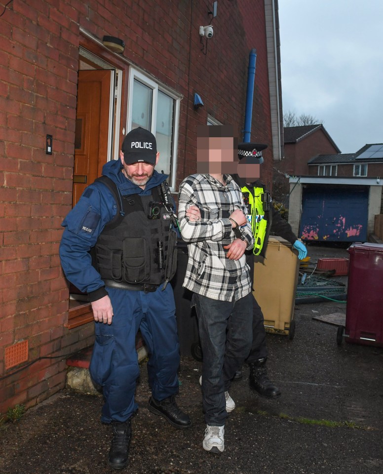 Police officers arresting a suspect outside a house.