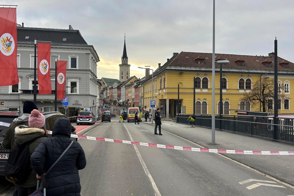 People looking at a cordoned-off area in Villach, Austria.
