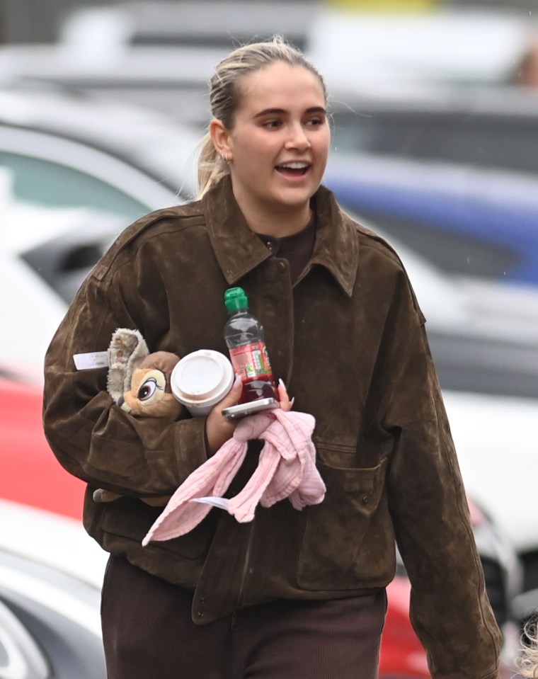Molly Mae Hague carrying a stuffed animal, drink, and other items.