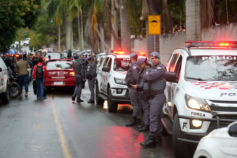 Police officers stand along a street near a plane crash site.