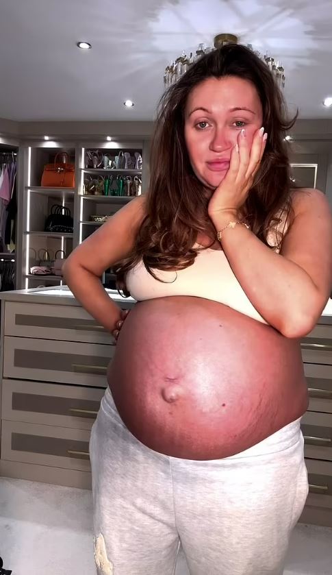 Pregnant woman holding her stomach, looking worried.