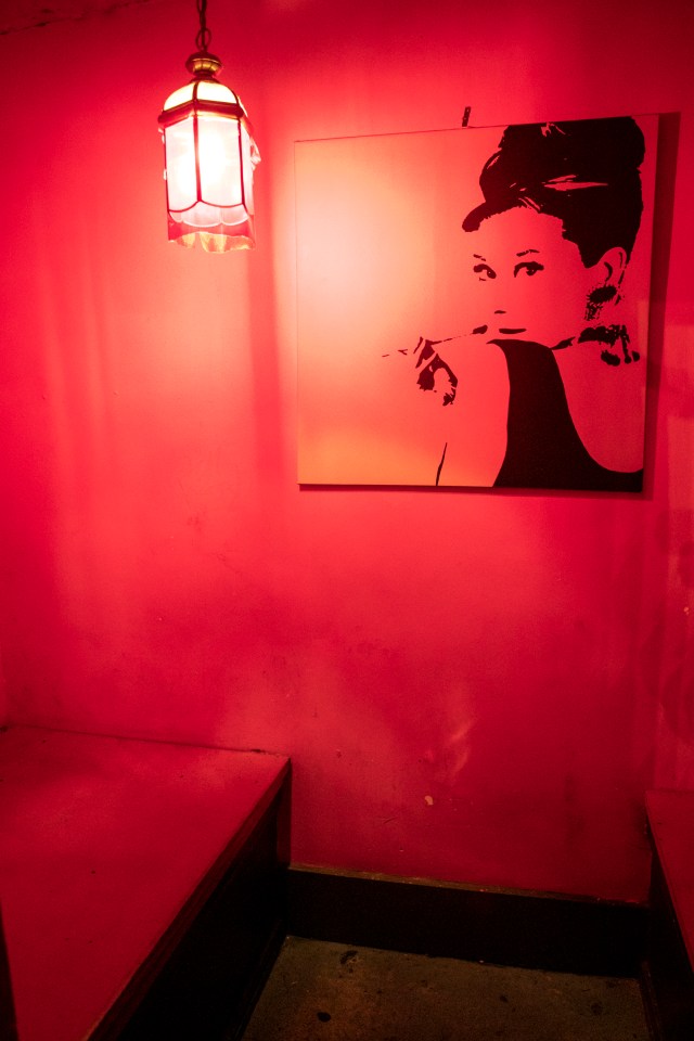 A red-lit room with a black and white Audrey Hepburn print and a hanging lantern.