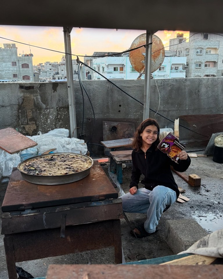 Girl on rooftop holding snack, with baked good on makeshift oven.