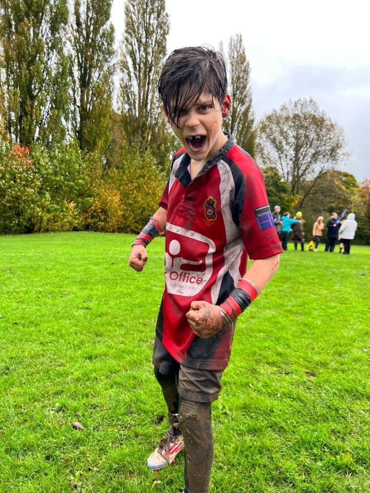Muddy boy in rugby uniform celebrating.