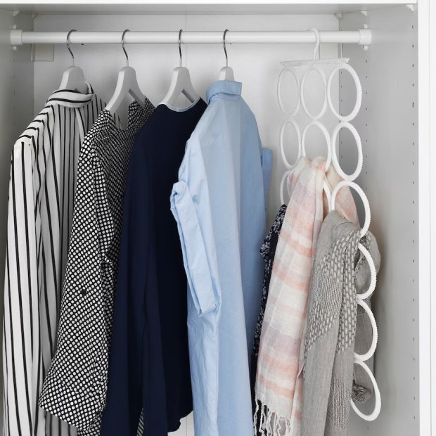 Clothes hanging in a closet with a scarf organizer.