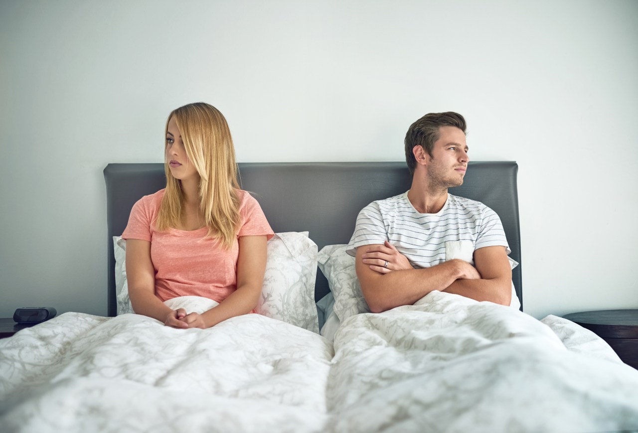 A young couple ignoring each other in bed.