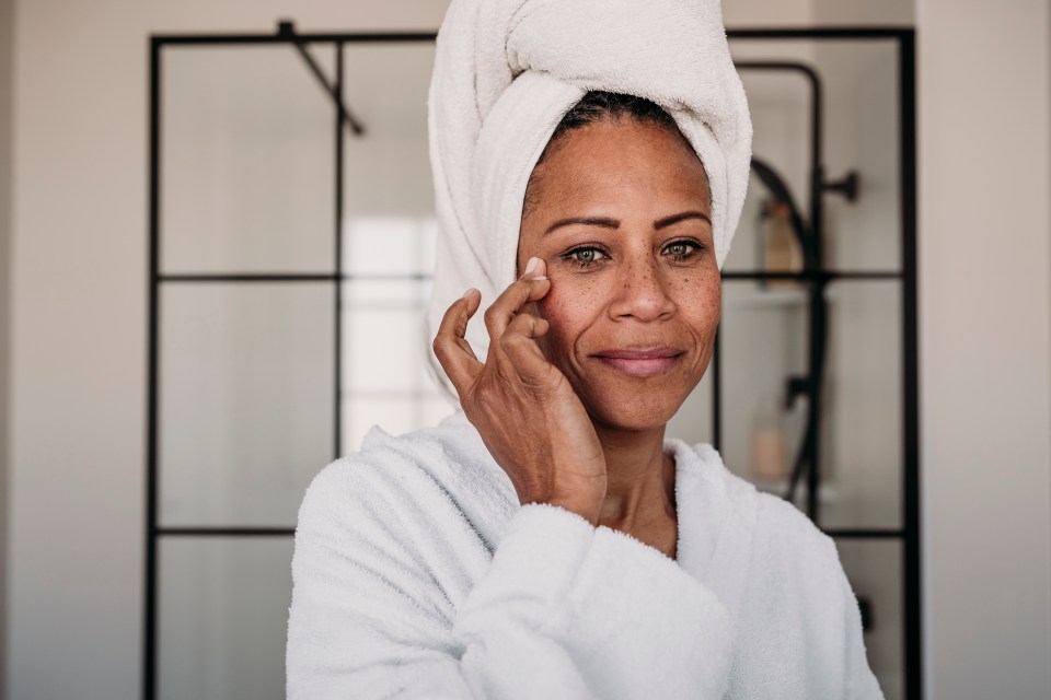 Woman applying moisturizer to her face.