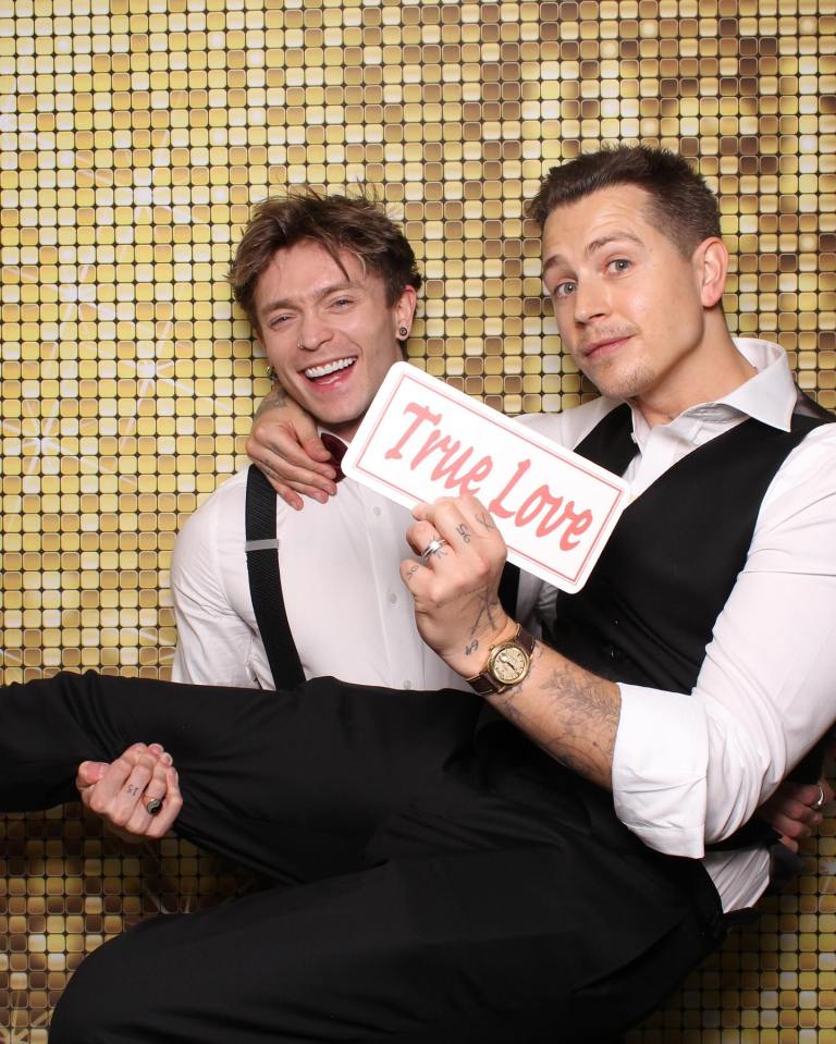 Two men holding a sign that says "True Love."