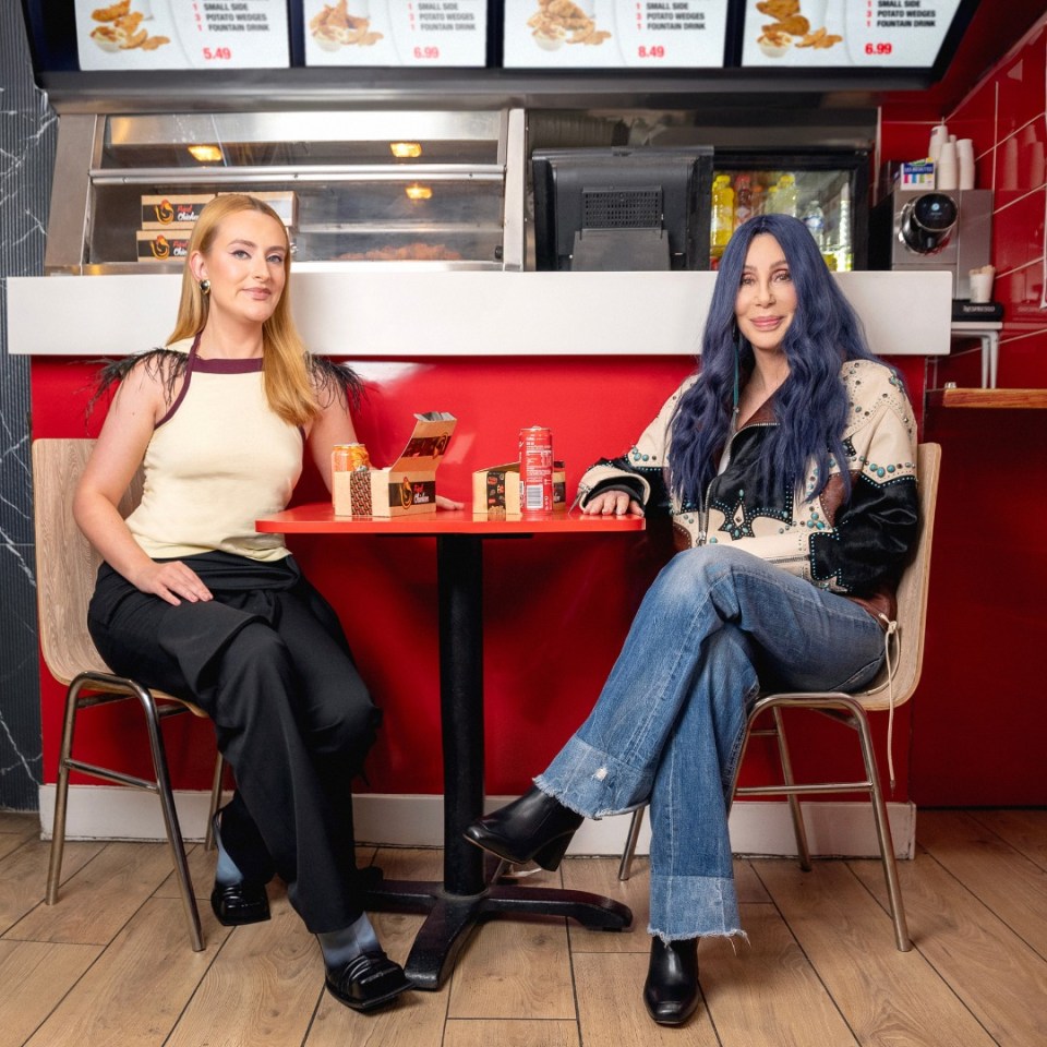Cher and Amelia Dimoldenberg sitting at a table in a chicken shop.