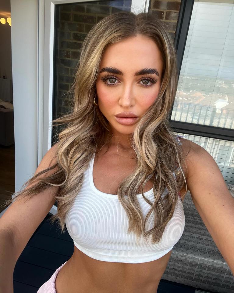 Selfie of a woman wearing a white crop top.