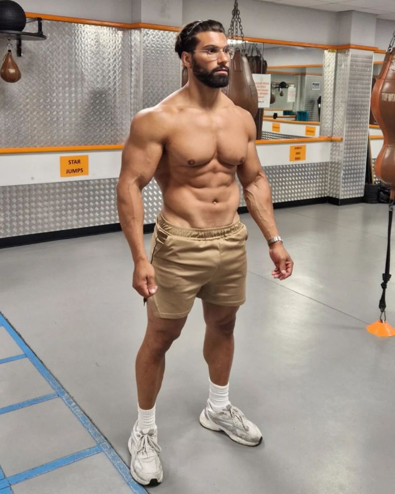 Muscular man in gym, wearing khaki shorts and sneakers.