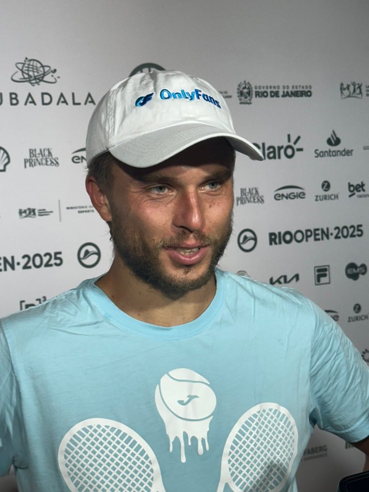 Man wearing a white OnlyFans baseball cap and light blue tennis shirt.