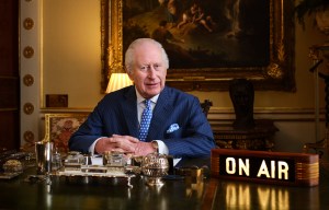 King Charles III sitting at a desk in Buckingham Palace, recording a radio broadcast.