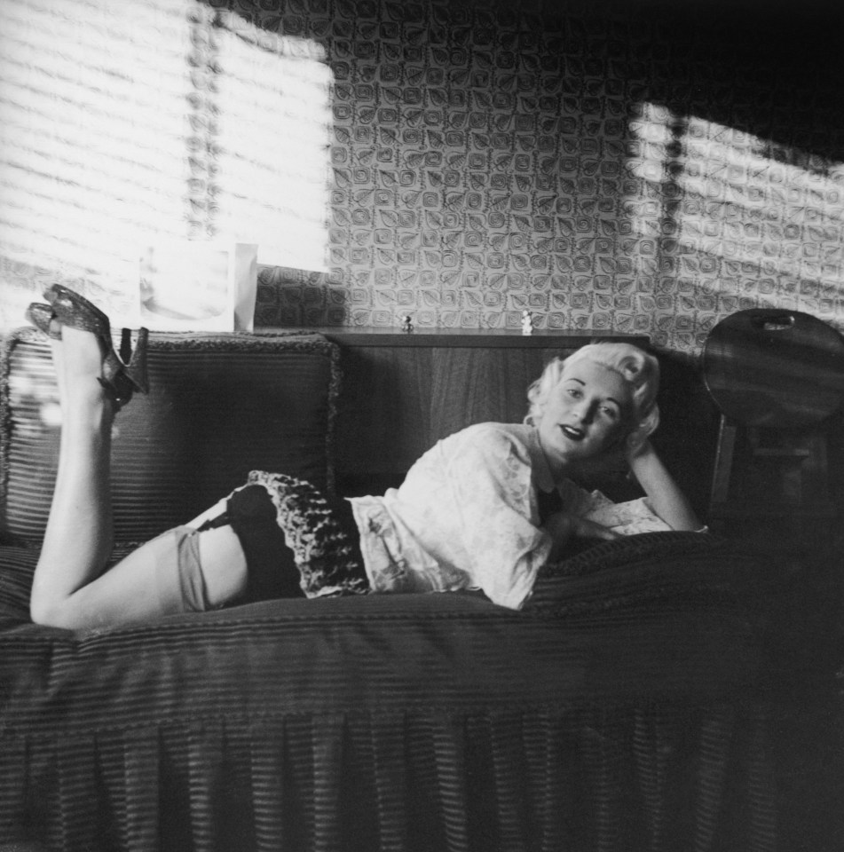 Black and white photo of Ruth Ellis, convicted murderer, posing on a bed in stockings and suspenders.