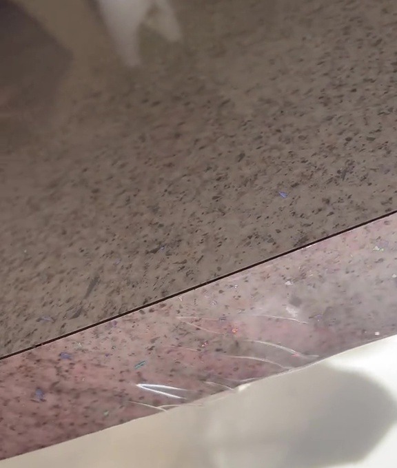 Close-up of a speckled countertop wrapped in plastic.