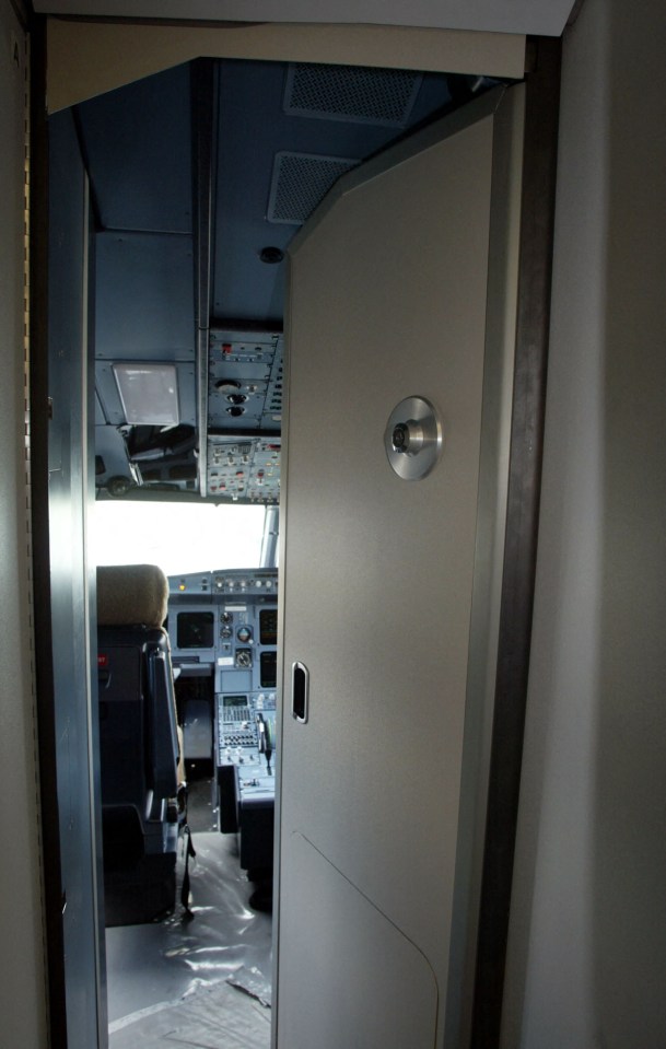 View of an Airbus cockpit through a reinforced security door.
