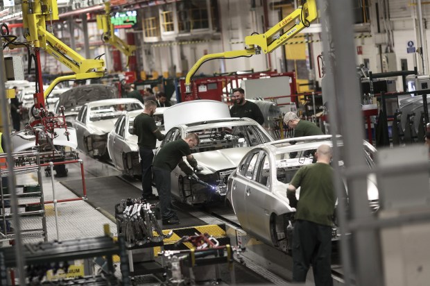 Workers assembling Jaguar XJ cars on a production line.