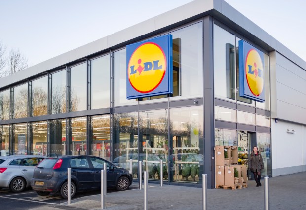 Exterior of a Lidl supermarket with a woman walking by.