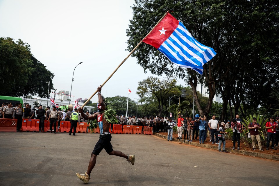 A Papuan student runs while carrying the West Papuan flag during a rally in Jakarta, Indonesia.