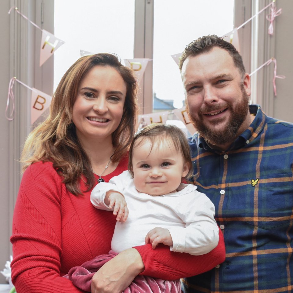 A photo of a family of three; a mother, father, and baby.