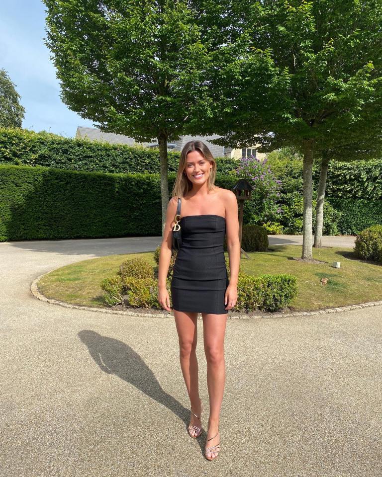 Woman in black dress standing outdoors.