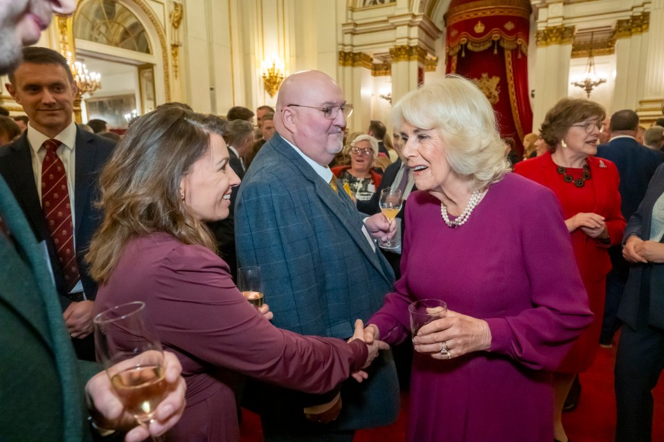 Queen Camilla shaking hands with Gill Smith at Buckingham Palace.