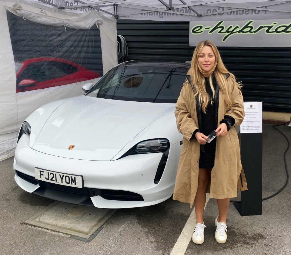 Woman standing next to a white Porsche Taycan.