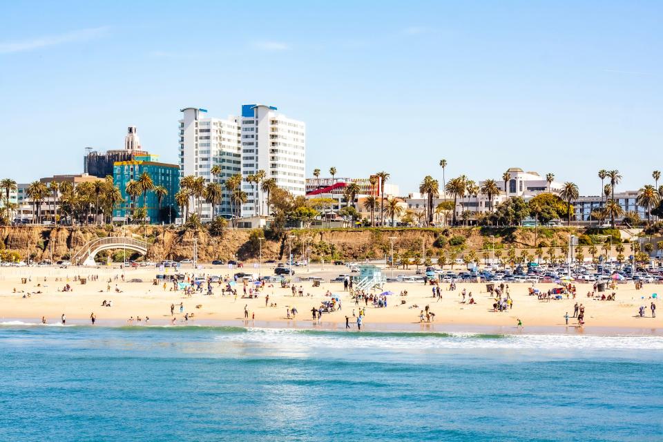 Santa Monica beach with people and buildings in the background.