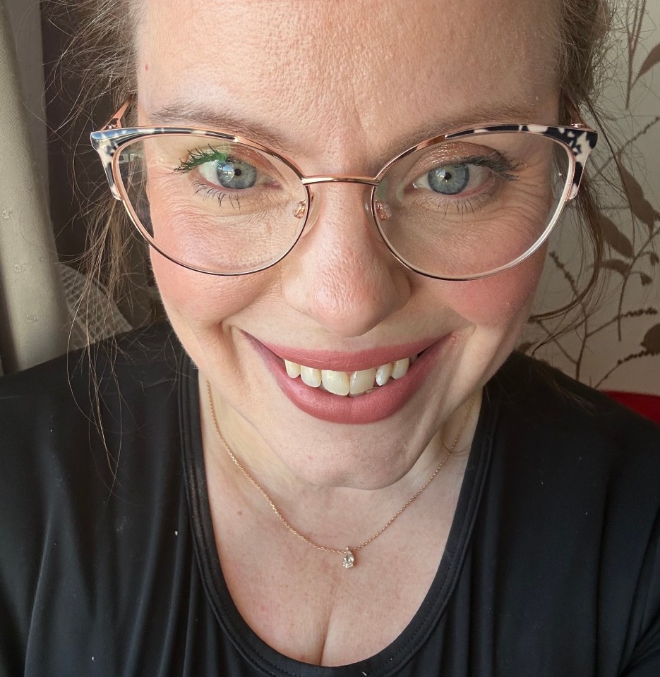 Close-up selfie of a woman wearing glasses and a necklace.