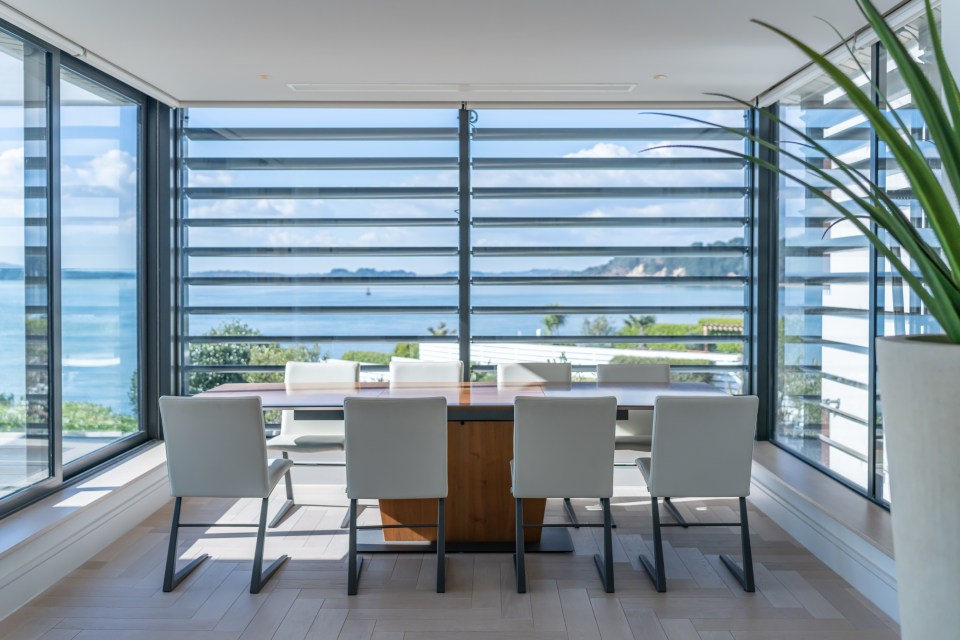 Dining table with six chairs facing a large window with a water view.